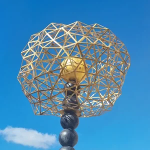 Gouden geodetisch bol sculptuur tegen blauwe lucht